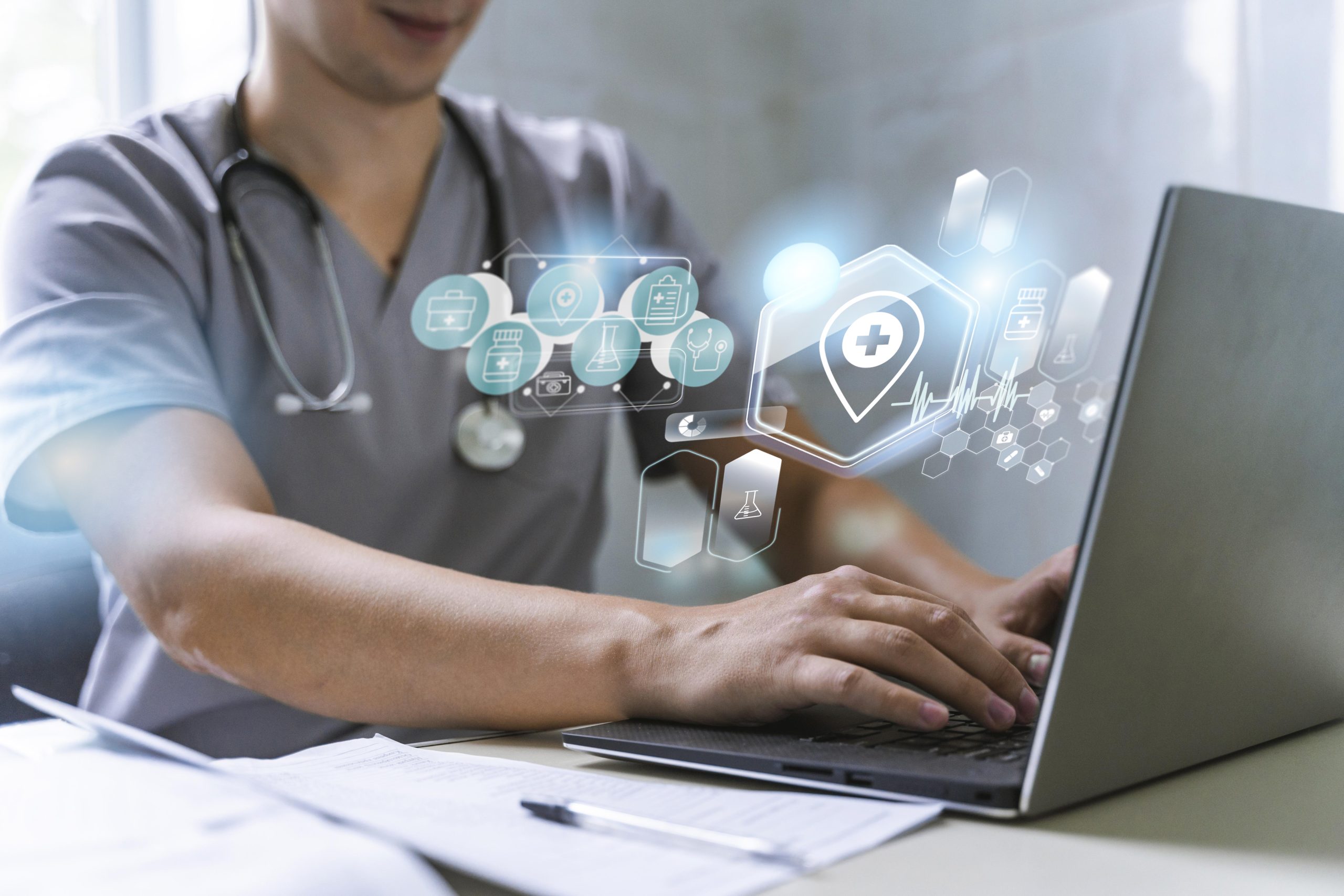 Doctor in scrubs with stethoscope using laptop with healthcare technology icons and digital medical data overlay