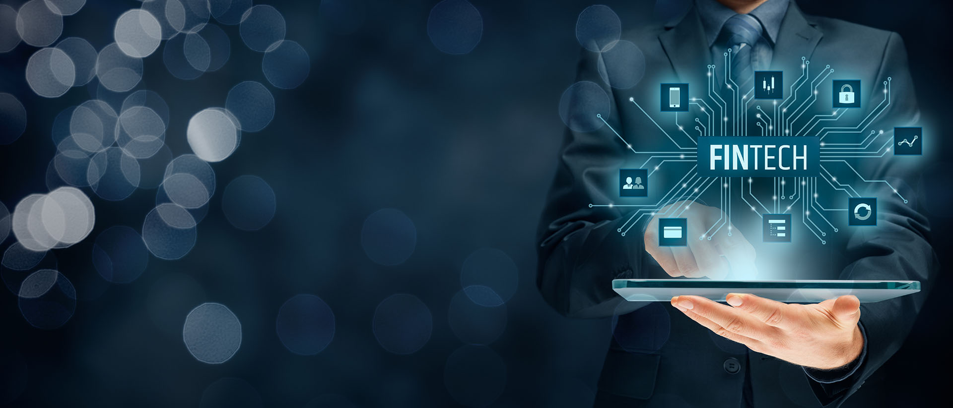 Businessman in suit holding tablet displaying FINTECH hologram with connected icons for security, payments, and analytics