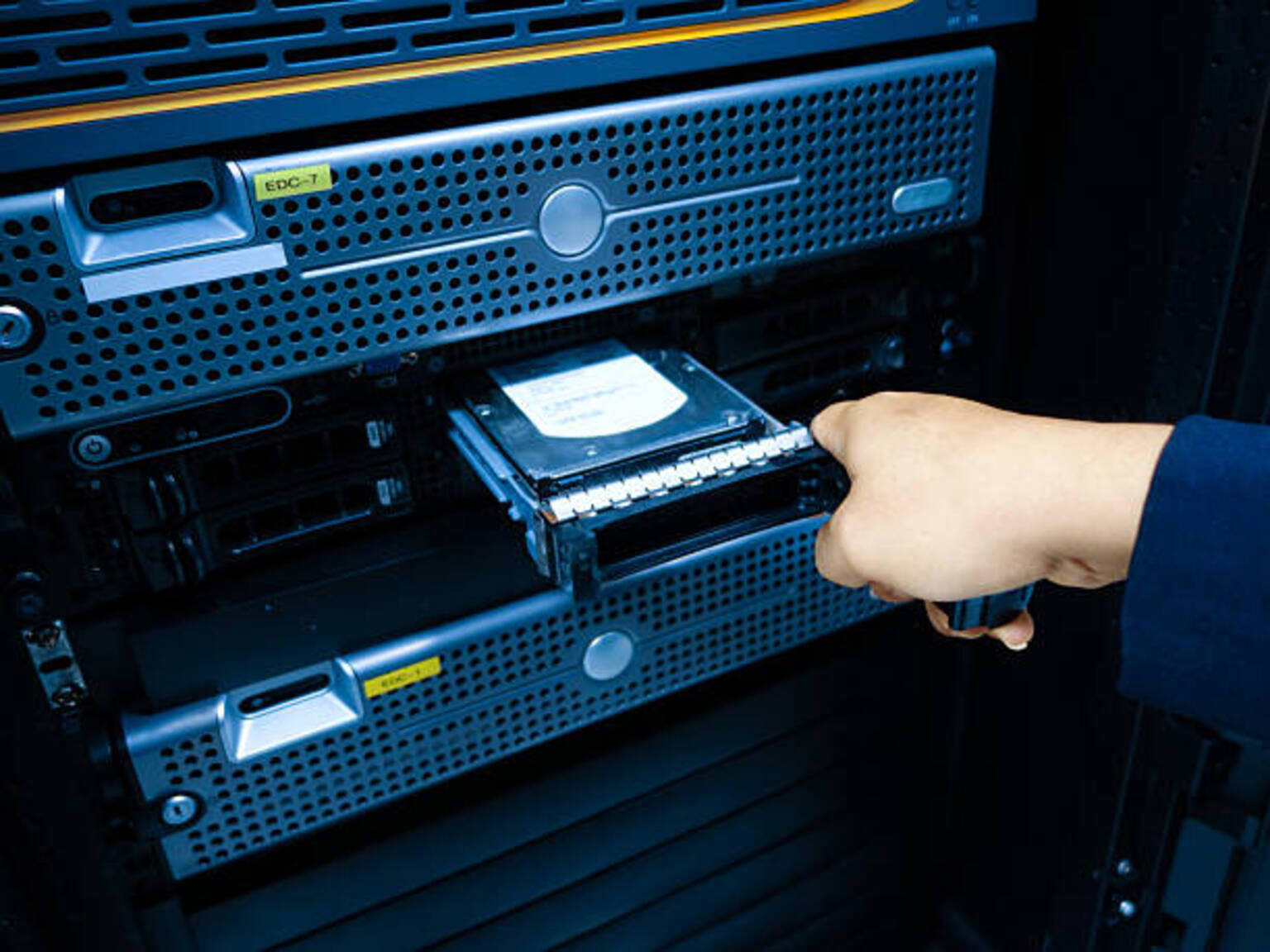 IT technician installing hard disk drive into enterprise server rack in secure data center for storage management